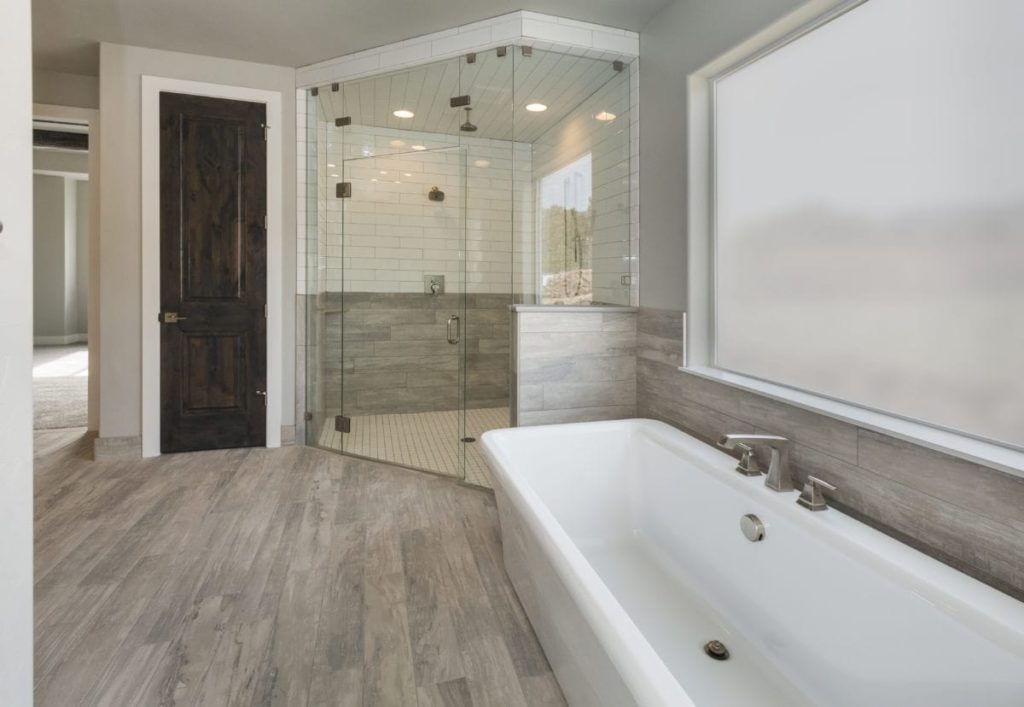 Bathroom remodeling project with glass walls, hardwood flooring and bath tub