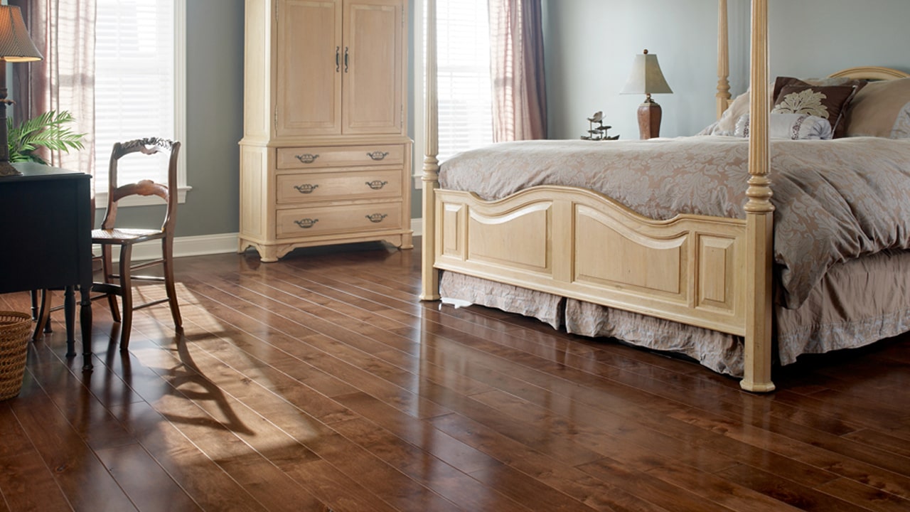 Bedroom flooring with a queen size bed and natural colored cabinet